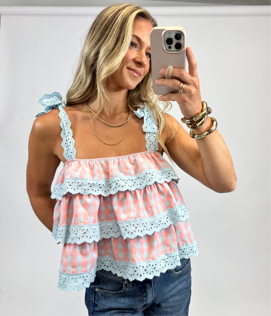 Model wearing the Tula Tank Top in coral and blue gingham with ruffle tiers and tie-shoulder straps from August Moon Boutique