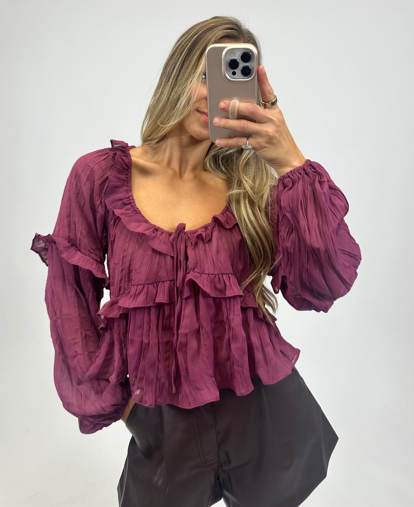 a burgundy ruffled blouse that is long sleeve with a scoop neckline