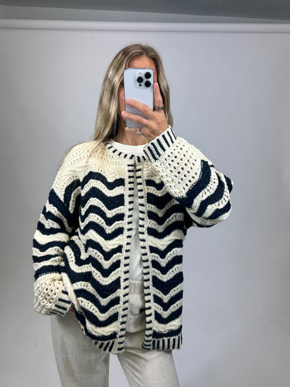 Person wearing a black and white striped sweater against a plain background